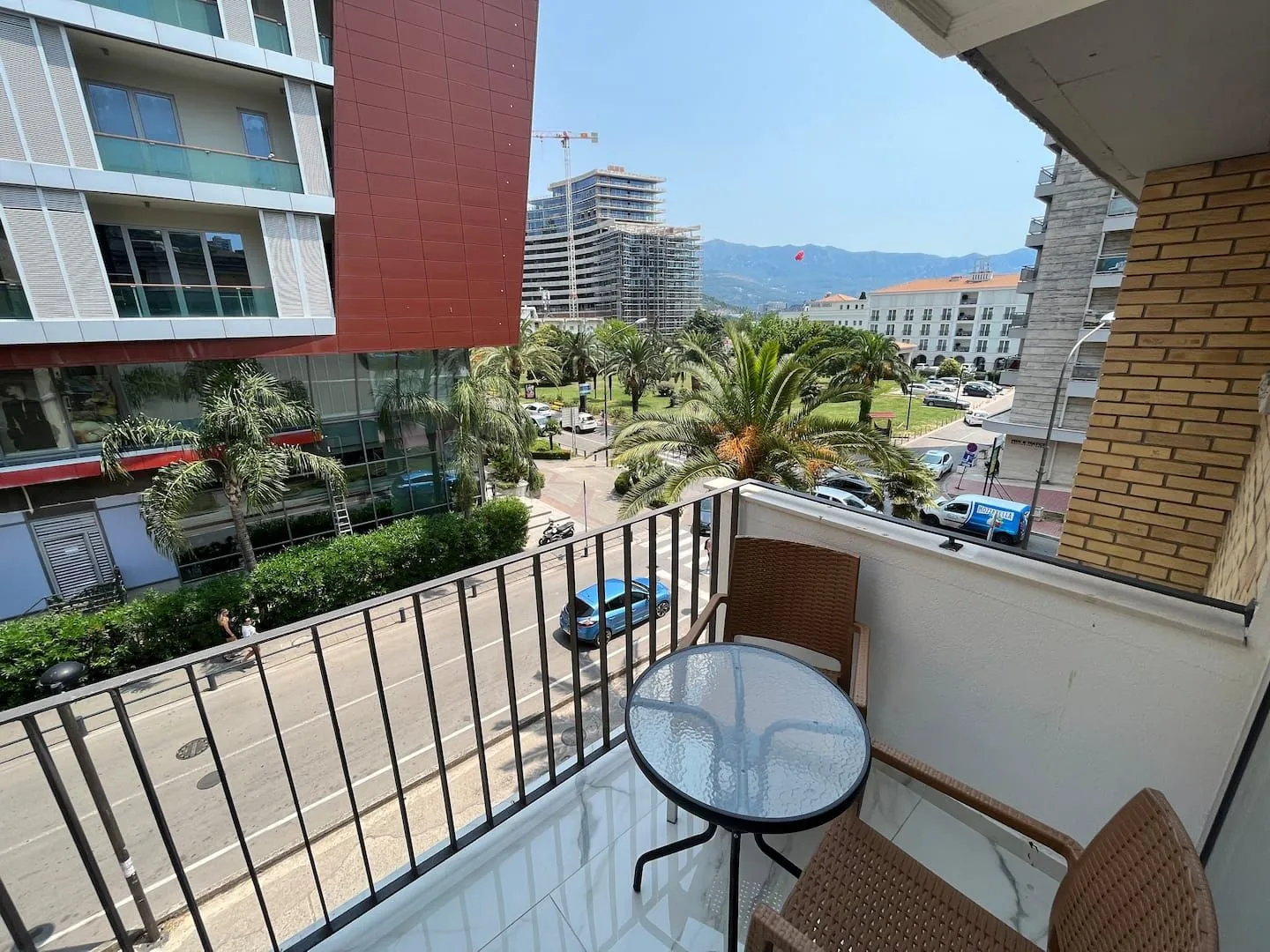 Small furnished balcony with a table and chairs and a city view.