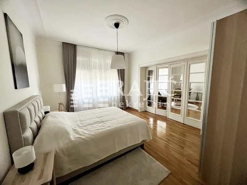 Spacious bedroom with a large double bed and wooden flooring.
