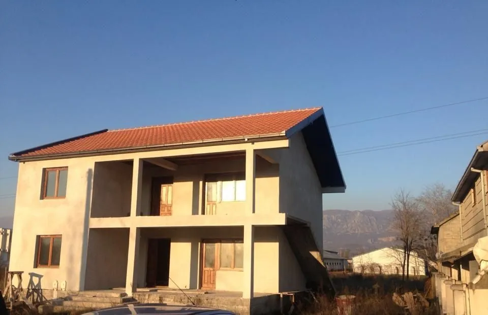 Dvospratna kuća u izgradnji sa crvenim krovom.