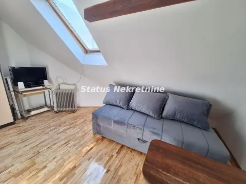 Attic living room with a grey sofa, television, and roof window. - image 4