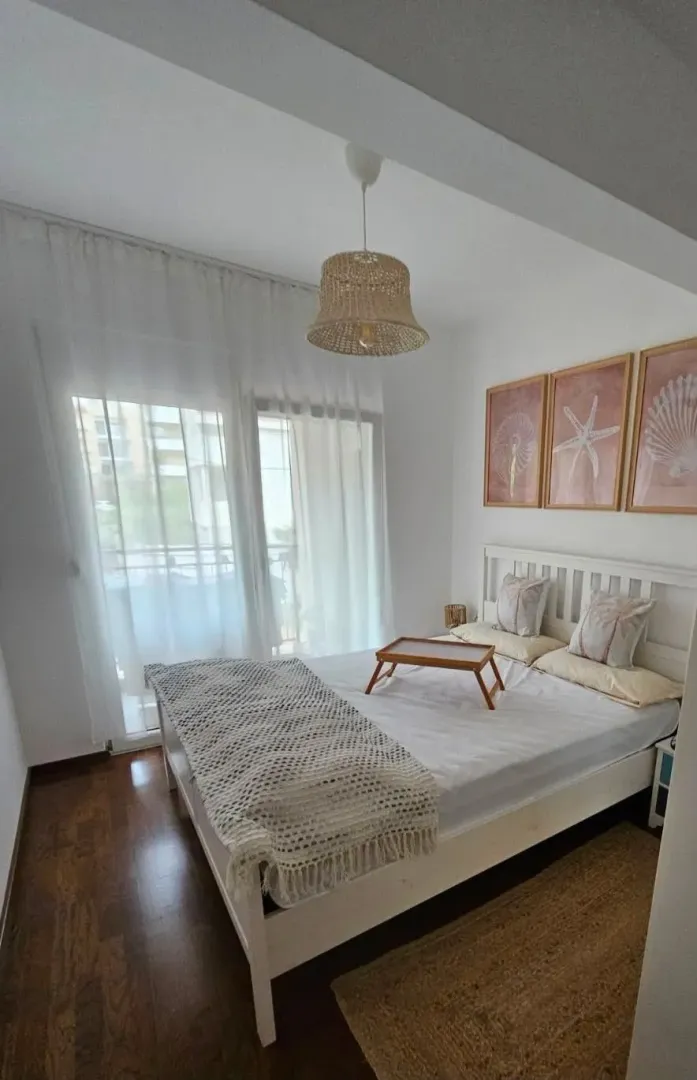 Bright bedroom with a double bed, balcony doors, and decorative wall art.