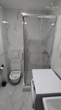 Modern bathroom with a shower cabin, toilet, and washing machine. - image 7