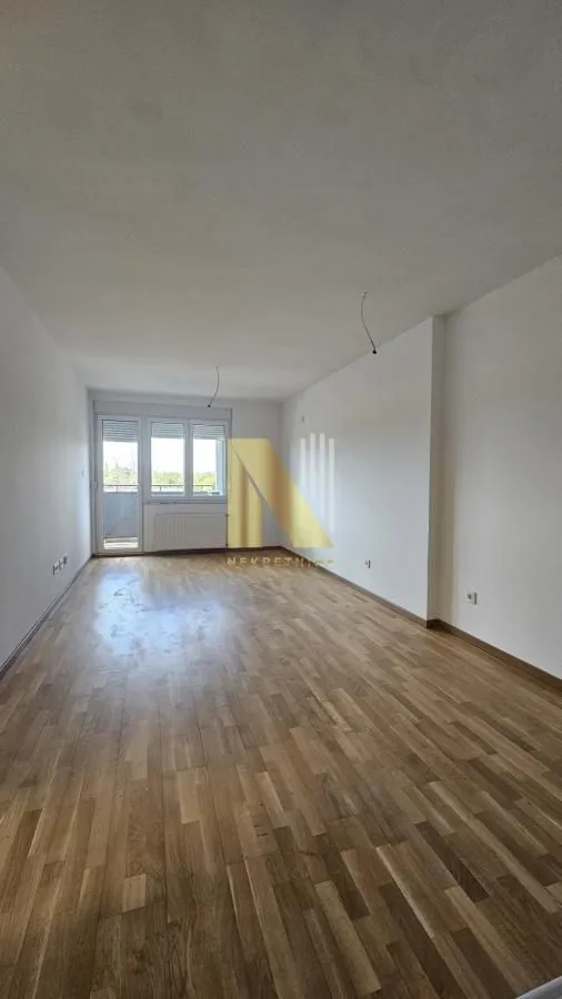 Prazna soba sa parketom i izlazom na terasu.