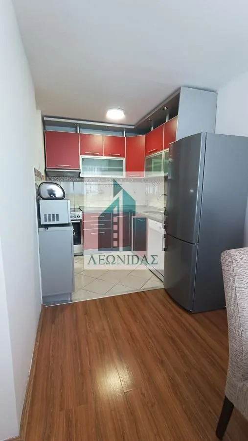 Manja kuhinja sa crvenim elementima i frižiderom.