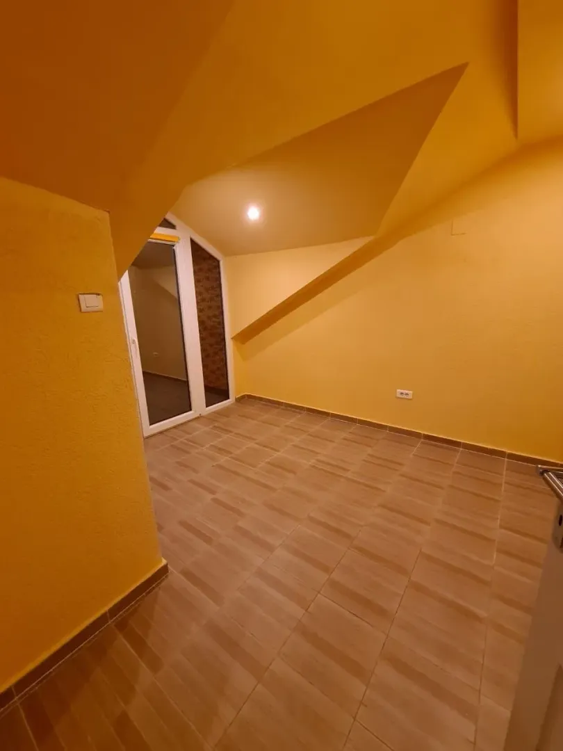 Prazna potkrovna prostorija sa žutim zidovima.