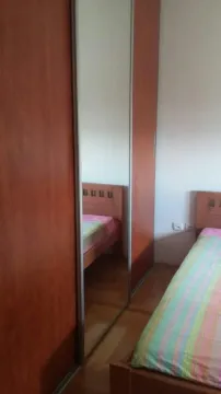 Simple bedroom with a wooden bed and a large built-in wardrobe. - image 2