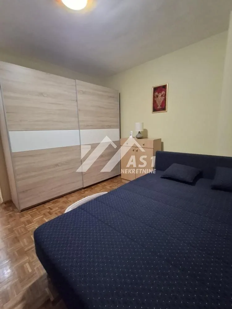 Nameštena spavaća soba sa bračnim krevetom i velikim ormarom.