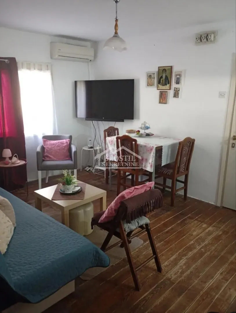 Living room with a sofa, dining table, and wall-mounted TV.