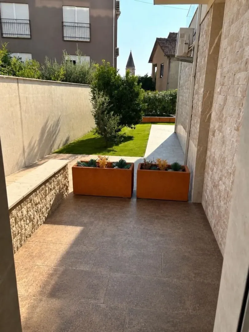 Uređeno dvorište sa popločanom stazom i travnjakom pored kuće.