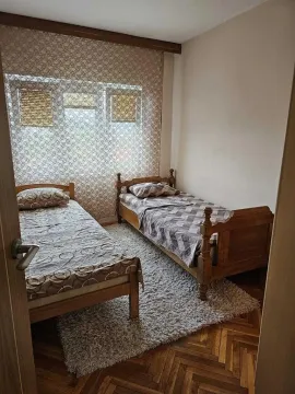 Spavaća soba sa dva drvena kreveta i tepihom. - image 17