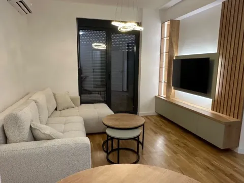 Dnevna soba sa ugaonom garniturom, TV komodom i drvenim oblogama na zidu. - image 2