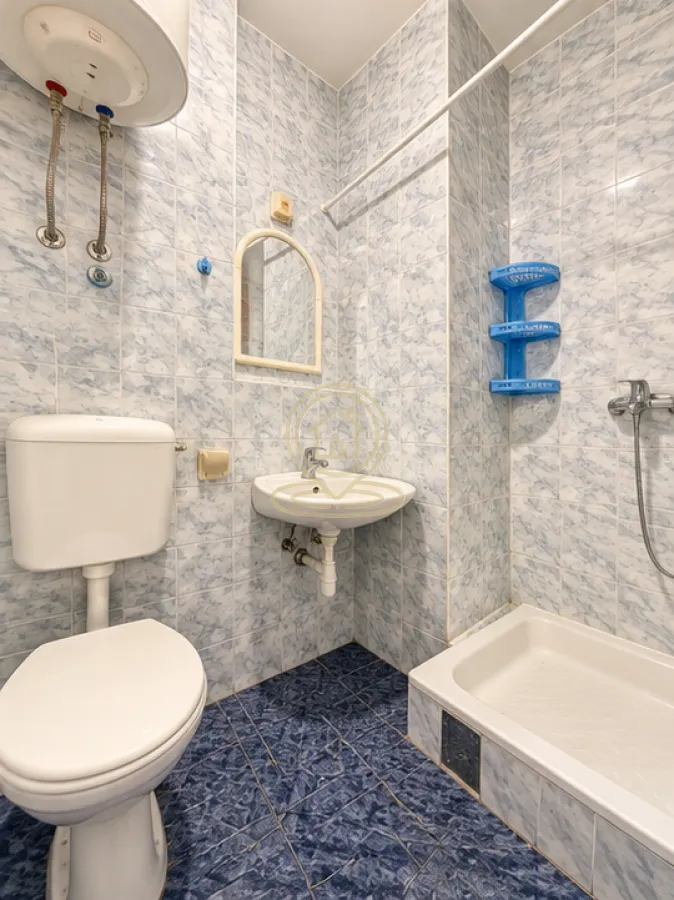 Manje kupatilo sa pločicama, umivaonikom, WC šoljom i tuš kabinom.