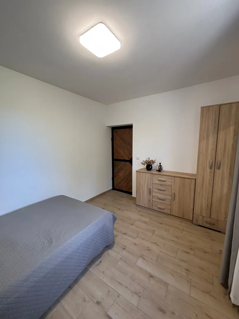 Namještena spavaća soba sa krevetom, drvenim ormarom i komodom.