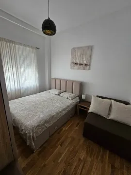 Furnished bedroom with a double bed, sofa, and wooden floor. - image 4