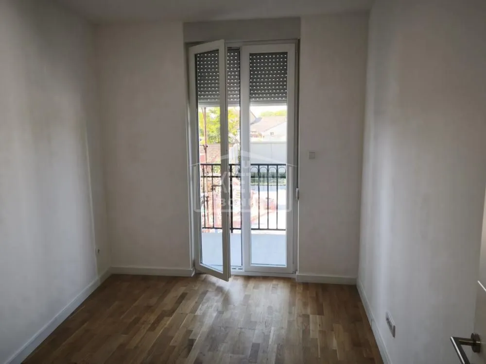 Prazna soba sa drvenim podom i izlazom na terasu.