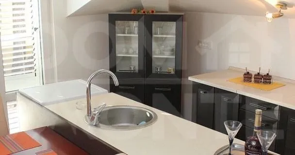 Moderna kuhinja sa šankom i tamnim elementima.