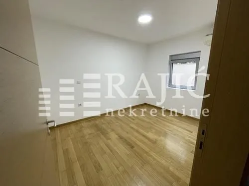 Empty room with wooden flooring and a window.