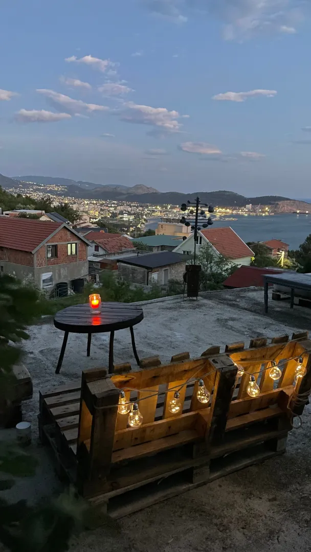 Terasa sa garniturom i pogledom na grad i more u sumrak.