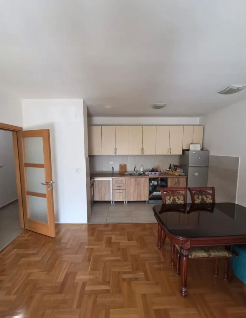 Kuhinja sa trpezarijom i drvenim podom u stanu.