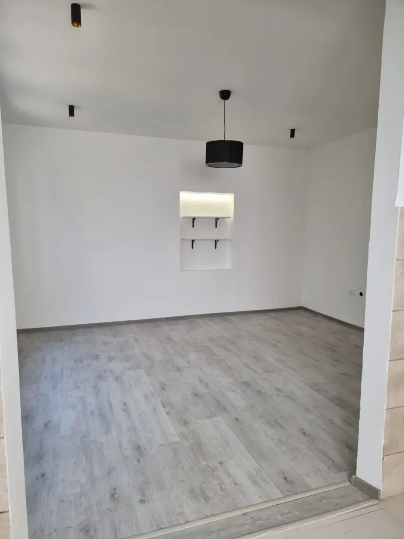 Empty room with laminate flooring and built-in wall shelves.