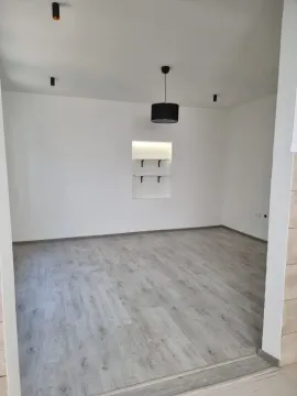 Empty room with laminate flooring and built-in wall shelves. - image 2