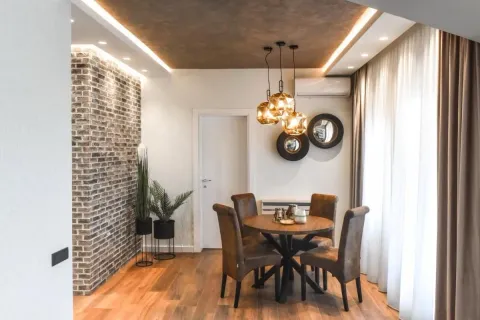 Trpezarija sa okruglim stolom i stolicama, dekorativnim zidom od cigle i modernim osvetljenjem. - image 16