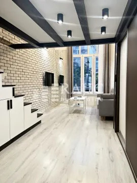Living room with light furniture, a brick wall, and ceiling beams. - image 7