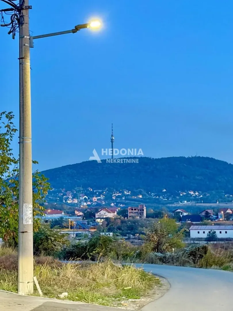 Pogled na brdo sa tornjem i naselje u sumrak.