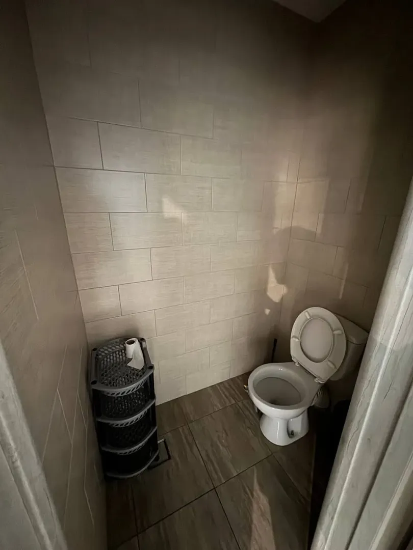 Small bathroom with toilet and tiled walls.