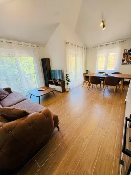 Spacious living room with a sofa, TV unit, and dining area. - image 13