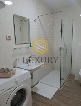 Modern bathroom with a shower cabin, washbasin, and washing machine. - image 9