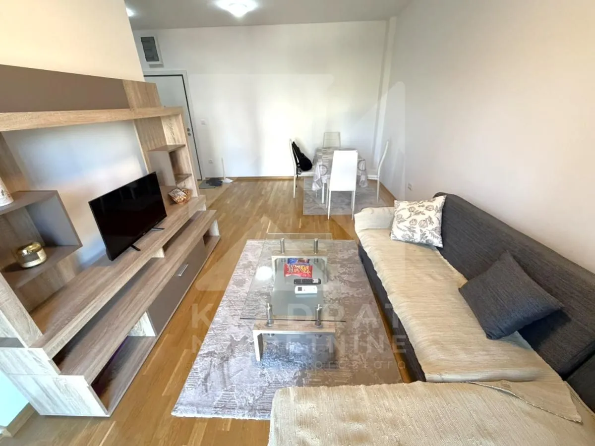 Living room with a corner sofa, TV unit and a dining area in the background.