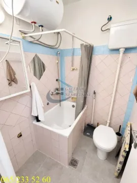 Manje kupatilo sa kadom, toaletom i pločicama na zidovima. - image 8