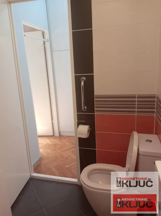 Pogled na kupatilo sa toaletom i pločicama u braon tonovima.