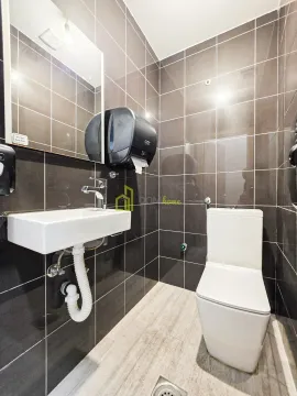 Small bathroom lined with dark tiles featuring a washbasin and a toilet. - image 5
