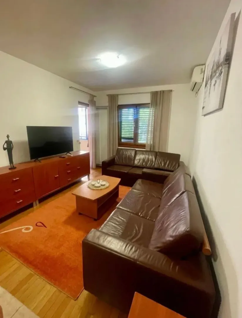 Dnevna soba sa garniturom, televizorom i komodom.