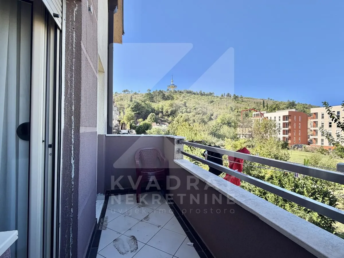 View from the balcony overlooking the surrounding greenery and hill.
