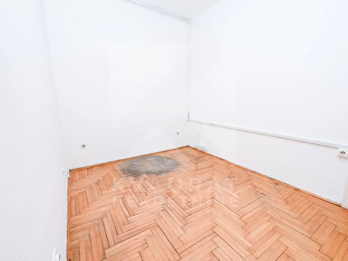 Empty room with white walls and parquet flooring.