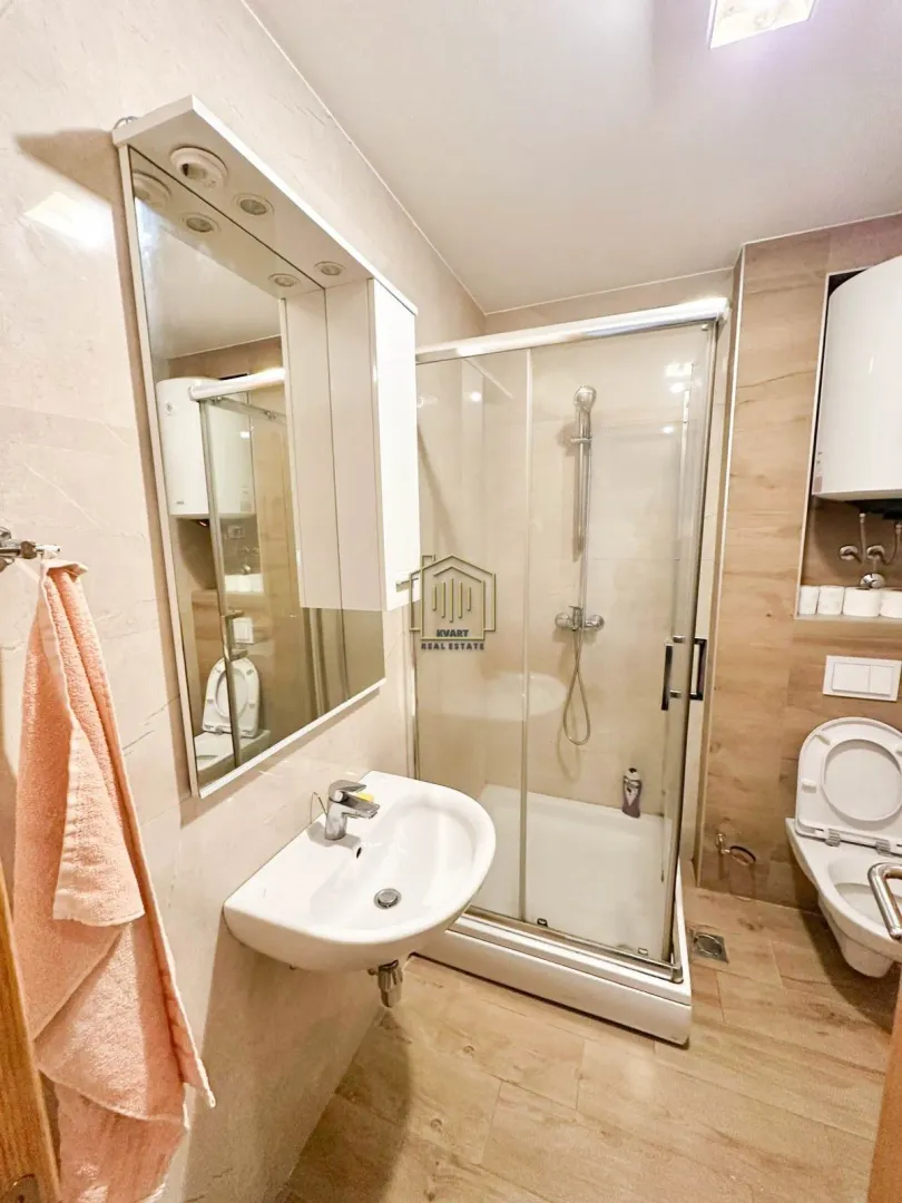 Compactly equipped bathroom with a shower cabin, sink, and toilet.