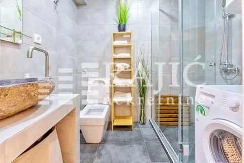 Moderno opremljeno kupatilo sa tuš kabinom, umivaonikom i wc šoljom.