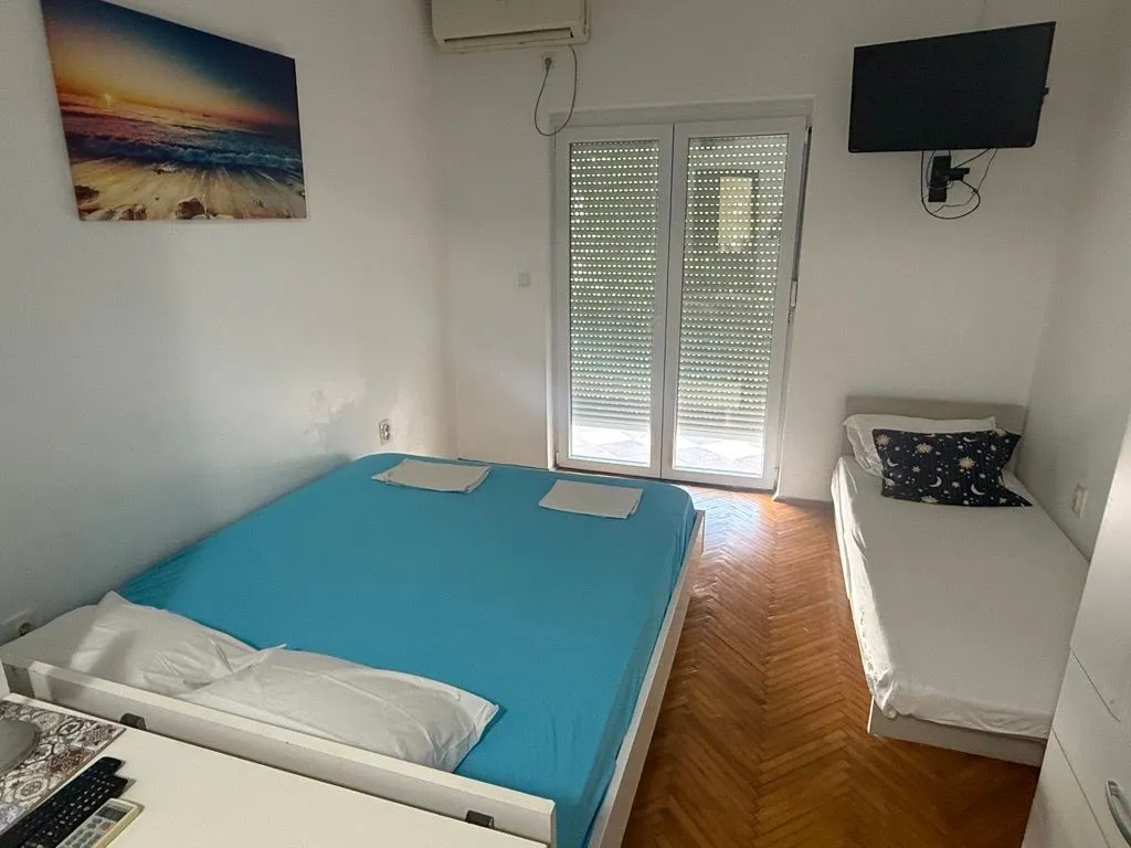 Spavaća soba sa dva kreveta i izlazom na terasu.