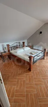 Potkrovna spavaća soba sa drvenim krevetom i keramičkim pločicama na podu. - image 4
