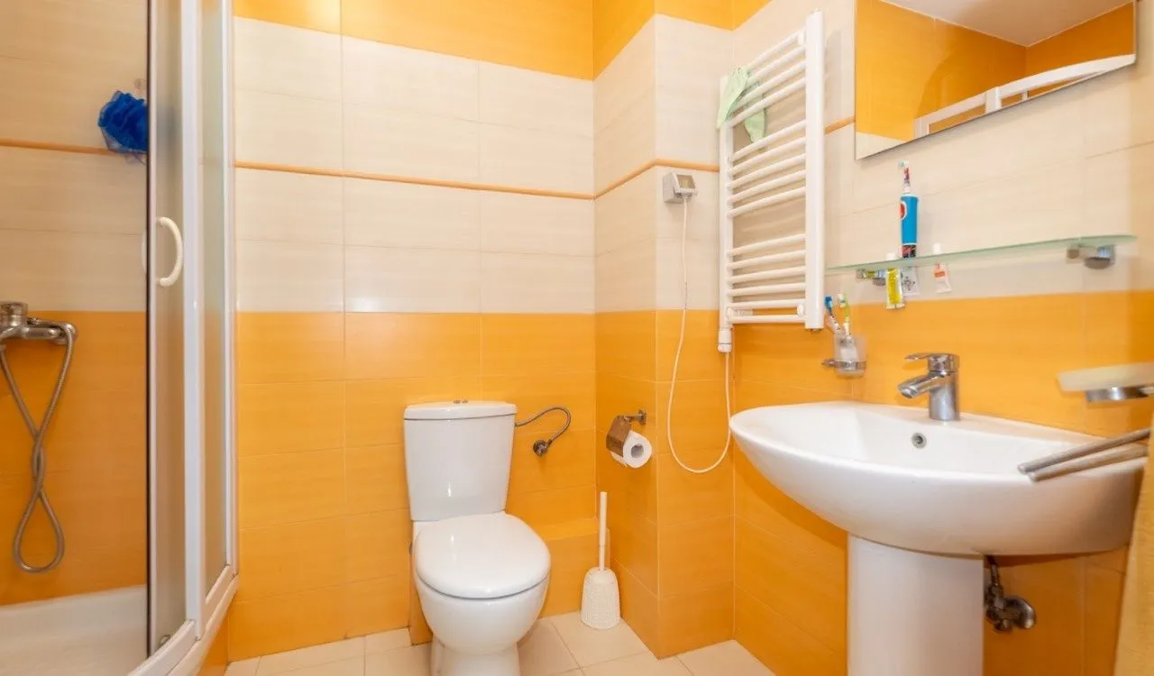 Kupatilo opremljeno umivaonikom, WC šoljom i tuš kabinom.