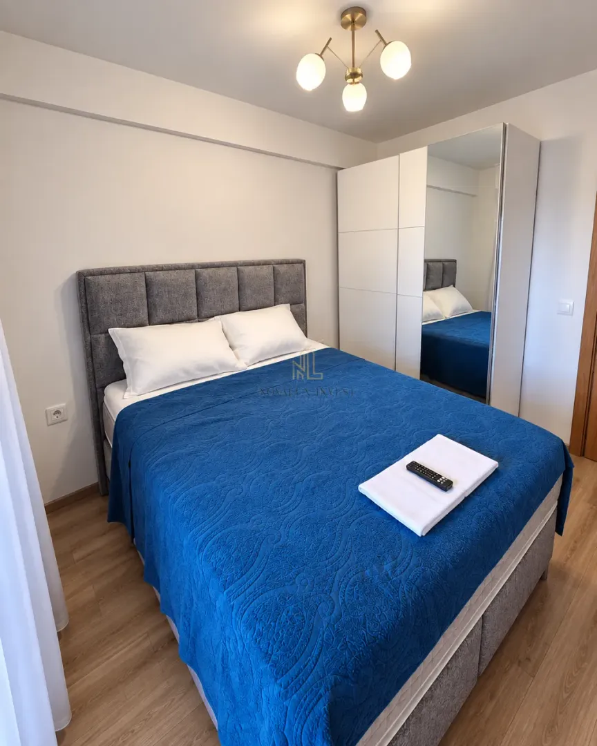 Furnished bedroom with a double bed and a wardrobe with a mirror.