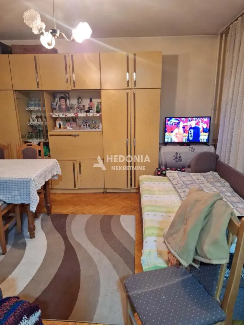 Living room with seating furniture, television, and wooden cabinets.