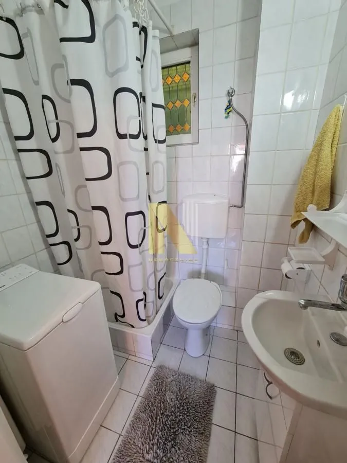 Manje kupatilo sa kadom, umivaonikom i veš mašinom.