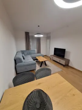 Living room with a sofa, TV console, and dining table in the foreground. - image 4
