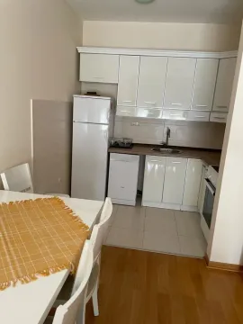 Bright kitchen with white cabinets and a dining table. - image 3