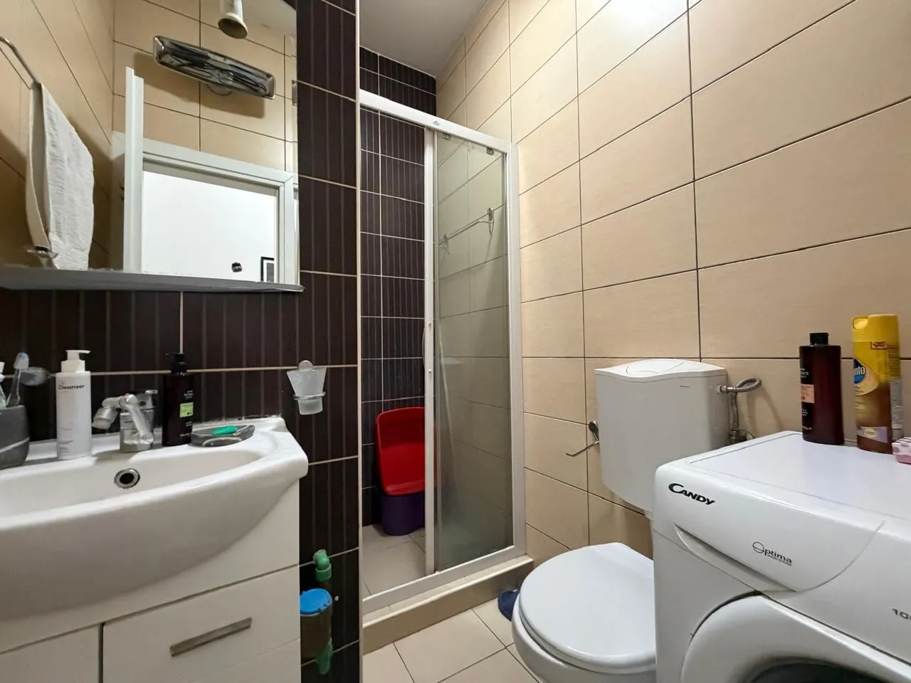 Manje kupatilo sa tuš kabinom, umivaonikom i veš mašinom.