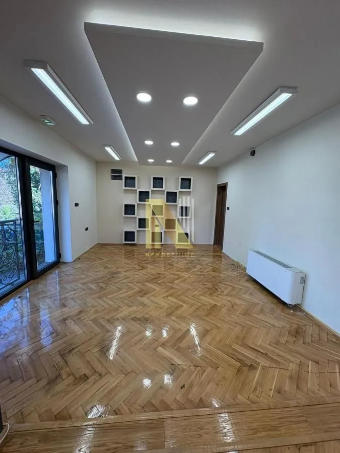 Empty living room with parquet flooring and a dropped ceiling with lighting.